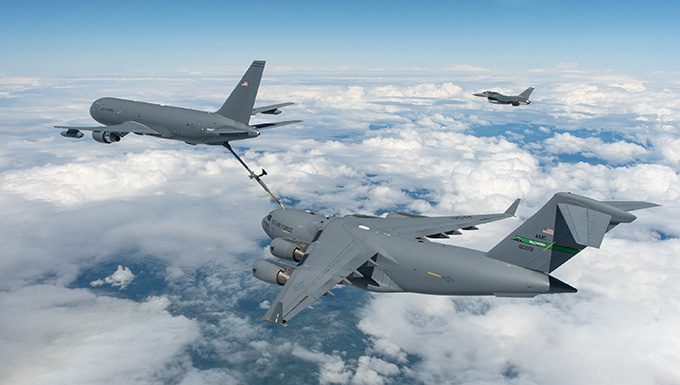 KC-46A refuling a C-5M over Seattle, Washington, with an F-16 Falcon flying in the background.